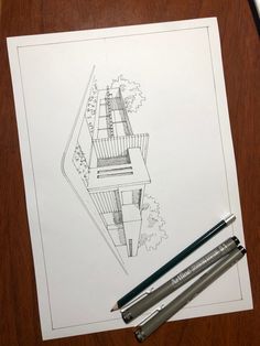 two pencils are sitting on top of a paper with a drawing of a house