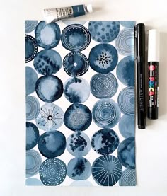 a blue and white paper with circles on it next to two markers, one pen and the other marker