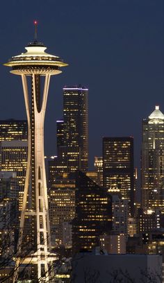 the space needle at night in seattle, usa with skyscrapers lit up behind it