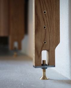 a close up of a wooden object on the ground near a wall with holes in it