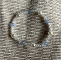 a white beaded bracelet with blue beads and glass beads on a gray fabric background