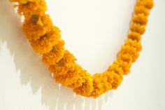 a yellow necklace with flowers hanging from it's sides on a white wall next to a clock