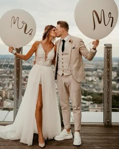 a bride and groom kissing while holding balloons with the word mr and mrs written on them