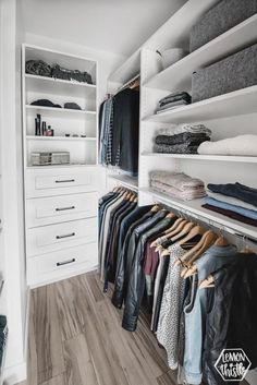 a walk in closet with white shelving and lots of clothes