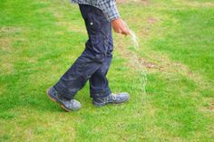 a man standing in the grass sprinkling with water from a hose on his feet