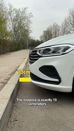 a white car parked on the side of a road next to a street sign that says distance is exactly 10 centimeters