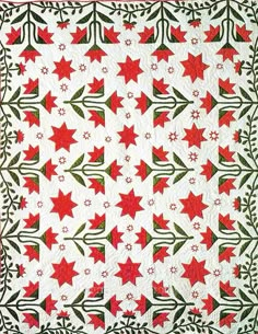 an orange and white quilt with red stars on the front, along with green leaves