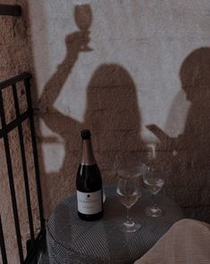 a bottle of wine sitting on top of a table next to two glasses and a cell phone