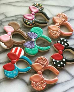 some decorated cookies are laying on a marble counter top with minnie mouse ears and bows