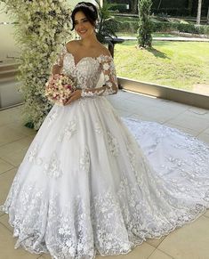 a woman in a white wedding dress standing on a patio with flowers and greenery