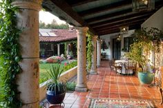 an outdoor patio with potted plants on the side and tiled flooring in front