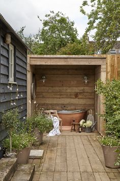 an outdoor bathtub in the middle of a wooden decked area with potted plants