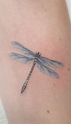 a blue dragonfly tattoo on the thigh