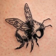 a black and white drawing of a bee on the back of a woman's shoulder