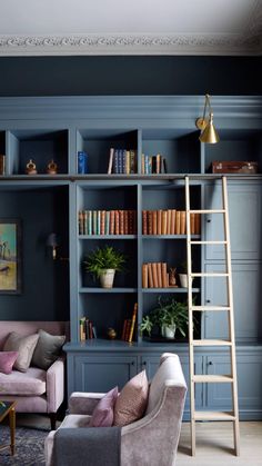 a living room with bookshelves, couches and ladder in the middle of it