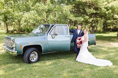 a bride and groom posing in front of a pick up truck