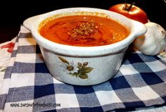 a white bowl filled with soup sitting on top of a blue and white checkered table cloth