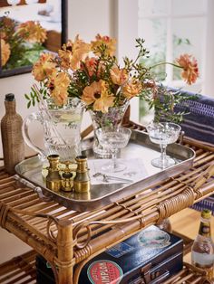 a wicker table topped with glasses and bottles filled with flowers on top of it