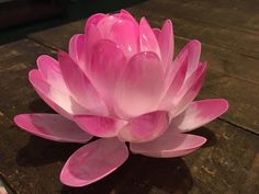 a pink flower sitting on top of a wooden table