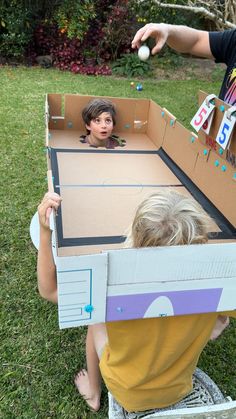 two children are playing in an open cardboard box