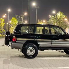 a black suv parked in a parking lot at night with its doors open and lights on