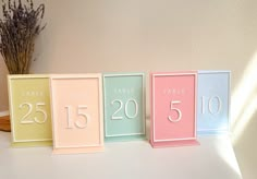 the table numbers are displayed in pastel colors on a white surface with dried flowers