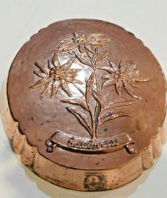 an old metal container with flowers on it's lid sitting on a white surface