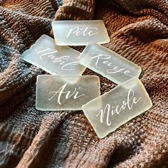 four pieces of glass sitting on top of a bed next to a brown blanket with writing on it