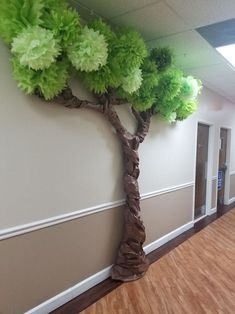 a tree that is sitting on the side of a wall in an office building with wood flooring