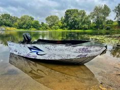 a boat is parked on the shore of a lake with trees and water in the background