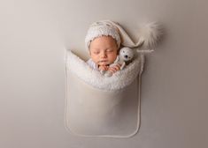 a baby sleeping in a white blanket with a stuffed animal