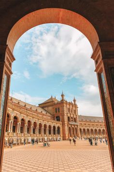 an arch in the middle of a courtyard with people walking around