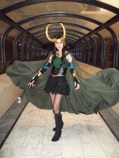 a woman dressed as loki in a hallway with horns on her head and cape around her neck