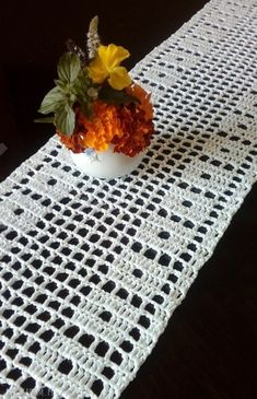 a crocheted table runner with flowers in a bowl