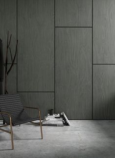 an empty chair in front of a wall with wood paneling on it and a plant next to it