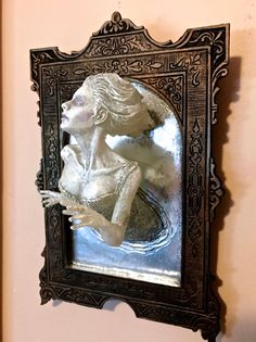 a mirror that is on the wall with a statue in it's reflection,