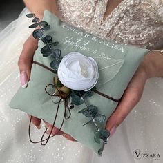 a woman holding a green pillow with a flower on it's side and the words crystal & albia written in cursive