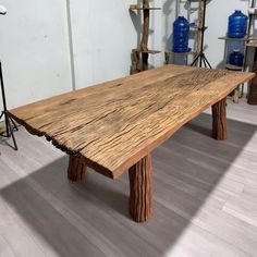 a large wooden table sitting on top of a hard wood floored floor next to blue vases