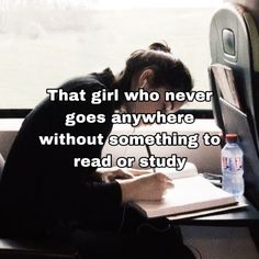 a person sitting on a train with their head down and writing in a notebook while looking out the window