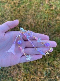 a person is holding out their hand with some beads on it and a fish charm hanging from the chain