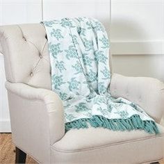 a chair with a blanket on top of it in front of a white wall and wooden floor