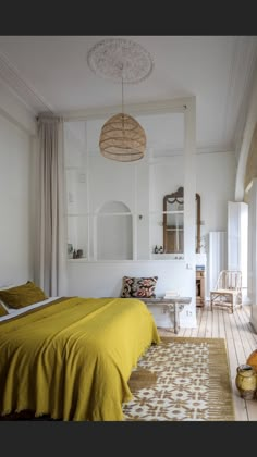 a bedroom with white walls and yellow bedding on the floor next to a window