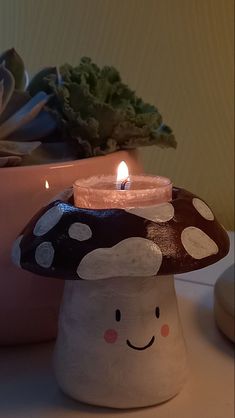 a mushroom shaped candle holder sitting on top of a table next to a potted plant