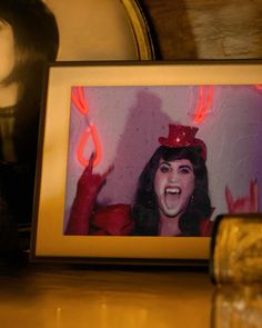 a framed photograph of a woman wearing a top hat and holding her hand up in the air