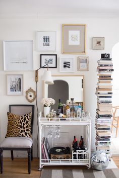 a living room filled with lots of furniture and pictures on the wall next to a chair