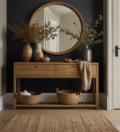 a wooden table topped with baskets under a round mirror