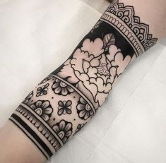 a woman's arm with a black and white tattoo design on her left arm