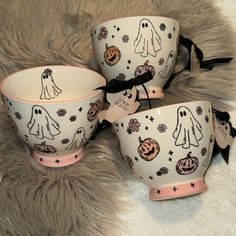 three halloween themed bowls with ghost faces and pumpkins on them, sitting on a furry surface