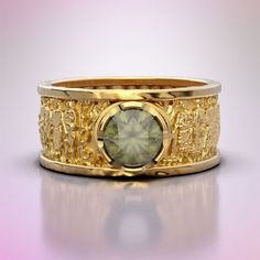 a yellow gold ring with a green stone in the center and ornate designs on it