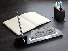 an open book and pen sitting on top of a desk next to a pen holder